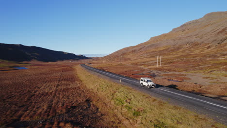 White-Landrover-Defender-Driving-Through-Empty-Road-In-Beautiful-Iceland-Outback-Nature-Landscape