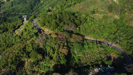 Aerial-circling-over-winding-road-through-lush-landscape-leading-to-Da-lat,-Vietnam