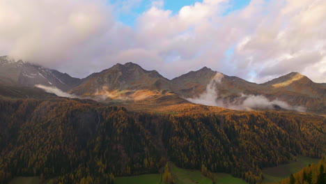 Glowing-golden-Casere-mountain-with-misty-low-cloud-over-autumn-alpine-valley-forest-trees