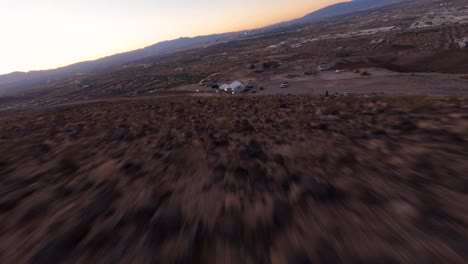 FPV-aerial-View-of-desert-dry-cracked-ground-fast-approaching-an-event-tent