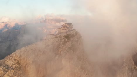 Nuvolau-rustic-cliff-hut-atop-Mount-Nuvolau-peak,-aerial-view-through-thin-cloud