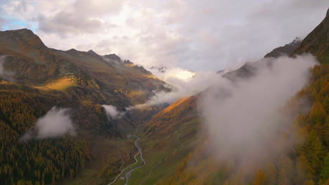 Stunning-low-cloud-creeping-through-Casere-Autumn-forest-South-Tyrol-valley-at-sunrise-aerial-view
