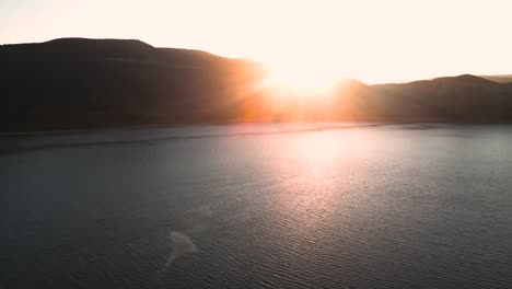 vail-lake-at-sunset,-sun-hiding-behind-mountains,-drone-view