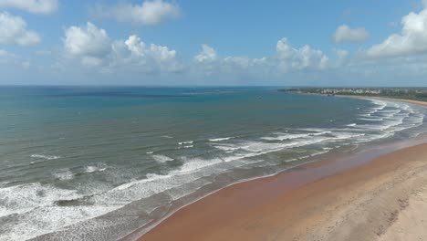 backward-aerial-view-of-a-large-sandy-bay-where-white-foamy-waves-arrive-on-the-shore