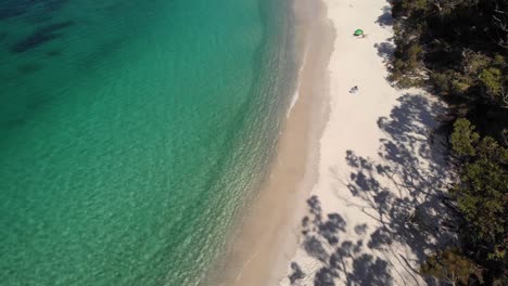 Aerial-view-overlooking-white-sand-and-turquoise-water-at-the-Murrays-Beach,-in-sunny-Jervis-bay,-NSW,-Australia---ascending,-tilt,-drone-shot
