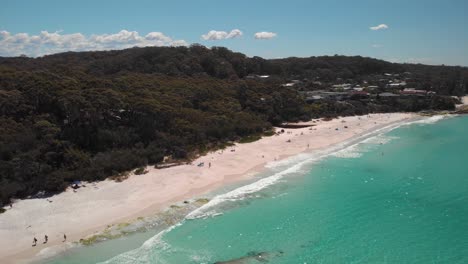 Aerial-view-overlooking-people-on-a-beach-in-Jervis-bay,-New-South-Wales,-Australia---pan,-drone-shot