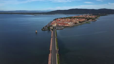 Time-lapse-of-cars-on-bridge-road-across-the-lagoon-toward-the-old-island-town-Orbetello-close-to-Monte-Argentario-and-the-Maremma-Nature-Park-in-Tuscany,-Italy,-with-water-reflections