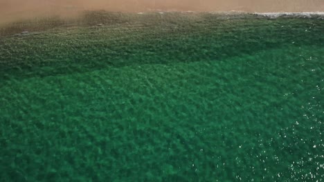 Aerial-view-of-a-beach,-in-sunny-Jervis-bay,-NSW,-Australia---reverse,-tilt,-drone-shot