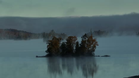 Aerial-flight-towards-island-on-lake-surrounded-by-fog