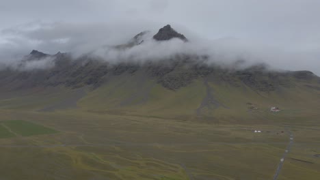 Grüne-Und-Flache-Isländische-Landschaft-Mit-Bergen,-Die-Von-Niedrigen-Wolken-Umhüllt-Sind,-Island