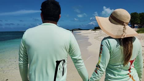 Back-view-of-Couple-walking-hands-to-hands-ON-WHITE-SAND-BEACH-looking-to-caribbean-sea,-honeymoon-concept