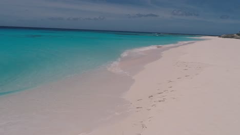 Couple-enjoy-Luxury-Caribbean-Beach-camp,-drone-shot-dolly-out-cayo-de-agua-island