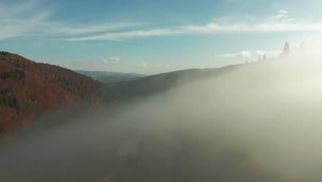 Aerial-flight-through-thick-fog,-above-mountainside-forest-in-full-autumn-color