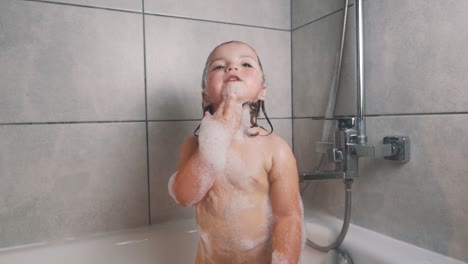 Hübsches-Kleines-Mädchen-In-Badeschaum,-Das-Mit-Einer-Zahnbürste-In-Ihren-Händen-Singt