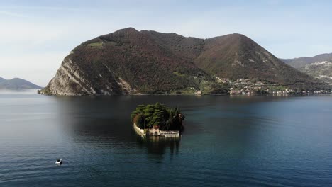Drone-rotates-around-San-Paolo-island-on-Iseo-lake-following-a-boat-revealing-the-panorama-lake