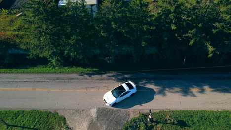 Aerial-drone-tracking-view-of-white-Audi-car-driving-and-turning-at-road-intersection-in-Cicero,-Indiana