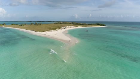 COUPLE-MAN-AND-WOMAN-SIT-ON-WHITE-SAND-BEACH-ALONE-LOOKING-CARIBBEAN-SEA,-CAYO-DE-AGUA,-DRONE-DOLLY-OUT