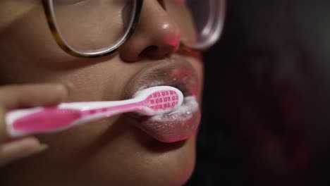 Black-woman-brushing-her-teeth-with-a-pink-brush-in-the-bathroom