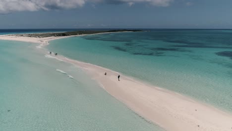 GIRL-SIT-ON-SANDBAR-BEACH-DAY,-AERIAL-DOLLY-IN-WHITE-SAND-TRAIL-BETWEEN-TWO-SEA-WATER