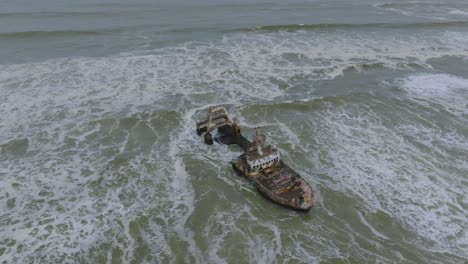 Waves-Crashing-on-Destroyed-Marine-Vessel-Shipwreck-in-Namibia,-Aerial