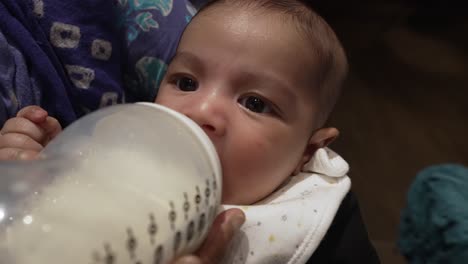 Entzückendes-2-Monate-Altes-Bangladeschisches-Baby,-Das-Milch-Aus-Der-Flasche-Trinkt,-Während-Er-Gewiegt-Wird