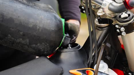 Man's-Hands-Pouring-Petrol-in-Motocross-Motorcycle-Tank---close-up-slow-motion