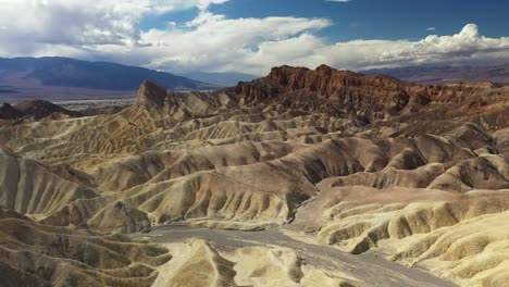 Vista-De-Drones-De-Las-Montañas-En-El-Desierto-Con-Un-Camino-Que-Pasa-Hermoso-Bajo-El-Cielo-Azul