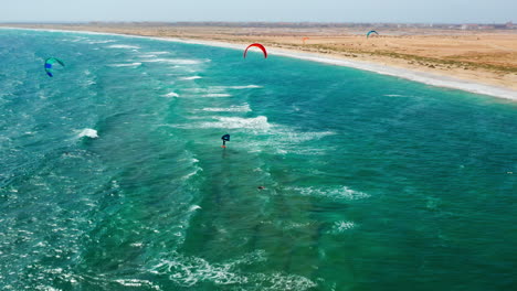 Vista-Aérea-De-Drones-De-Kiters-Profesionales-Surfeando-En-Sal,-Cabo-Verde