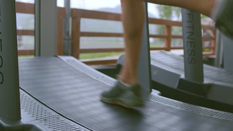Feet-of-a-person-running-and-training-on-a-curved-treadmill-inside-a-gym,-low-angle-close-up-of-fitness-concept
