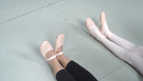 Close-up-of-young-ballerinas-stretching-their-legs-and-feet,-training-session