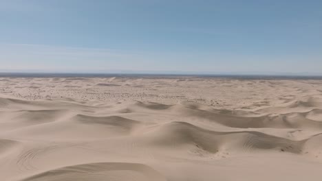 Flying-Over-Vast-and-Majestic-Open-Desert-Landscape,-Aerial-Drone-Shot-with-Blue-Sky-and-Soft-Sand