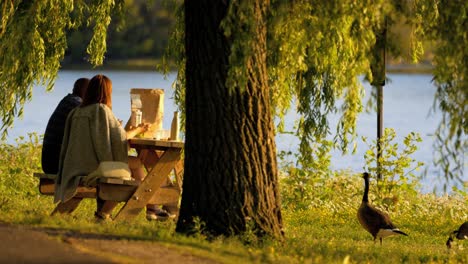 Couple-having-picnic-by-river-at-sunset-slow-motion