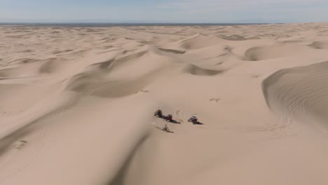 Fly-By-Shot-Revealing-ATV-Dune-Buggies-Driving-Through-Sandy-Desert-Peaks-on-Sunny-California-Day