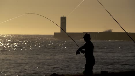 Silhouette-Fischer-Fischen-An-Der-Küste-Meer-Frischer-Fisch-Epischer-Sonnenuntergang-Hintergrund