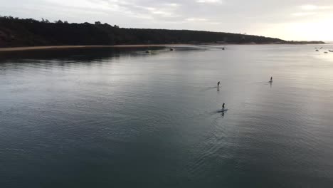 Standup-Paddleboarders-paddling-in-sunset-Milfontes,-Portugal-Orbiting-Aerial