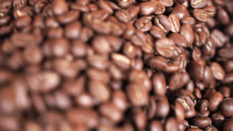 Close-up-roasted-coffee-beans-being-pushed-through-drum-roaster-in-slow-motion