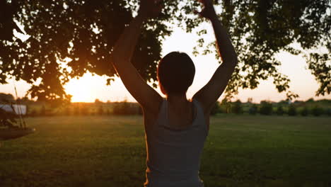 Short-haired-woman-does-jumping-jacks-while-facing-a-beautiful-sunset