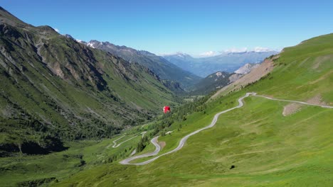 Paraglider-fly-above-Col-du-Glandon-Mountain-Pass-in-French-Alps---Aerial-Static-Shot