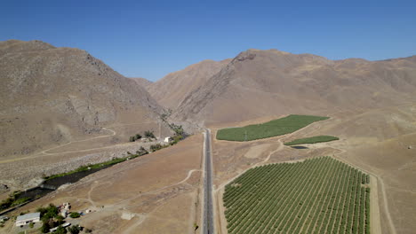Luftaufnahme-Des-Grünen-Fleckens-Landwirtschaftlich-Genutzter-Flächen-In-Der-Wüstenlandschaft-Mit-Tal-In-Der-Ferne-In-Kalifornien