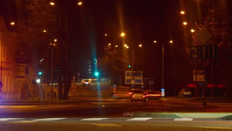 Timelapse-of-city-rush-hour-traffic,-Liepaja-city-streets,-city-at-night-landscape,-traffic-light-streaks,-lights-glowing-in-mist,-distant-medium-shot