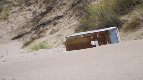 Old-white-refrigerator-on-the-beach,-trash-and-waste-litter-on-an-empty-Baltic-sea-white-sand-beach,-environmental-pollution-problem,-overcast-day,-distant-medium-shot