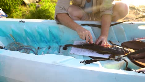 A-man-cutting-into-the-meat-of-a-flathead-fish-on-his-kayak-in-Australia