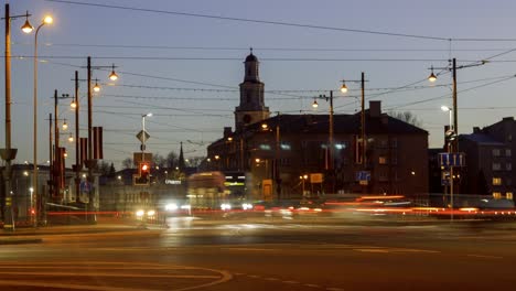 Timelapse-of-city-rush-hour-traffic-over-the-Liepaja-tram-bridge,-city-landscape,-traffic-light-streaks,-fast-moving-trams,-distant-medium-shot