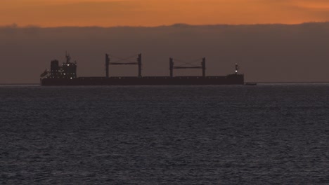 Big-ship-sailing-in-the-sea-at-sunset-with-small-boat-leaving-faster