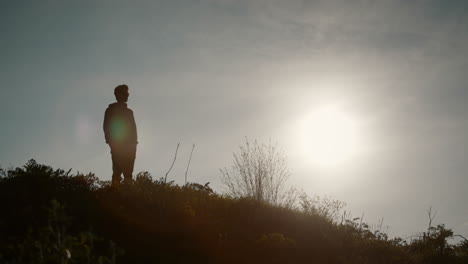 Man-looking-in-the-valley-,-silhouette-effect,-big-sun,-clear-sky