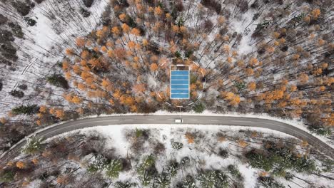 Aerial-top-down-of-white-electric-car-driving-through-winter-landscape-with-animation-showing-battery-levels