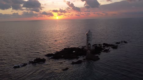 Breathtaking-aerial-view-of-lighthouse-on-offshore-rocks-in-Calasetta,-sunset