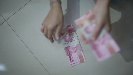 female-hands-counting-by-dropping-money-on-floor-with-change-focus