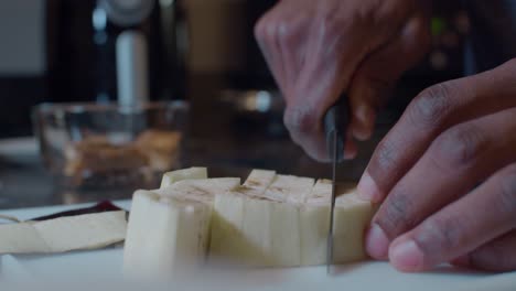 Man-dicing-fresh-ripe-peeled-eggplant-on-plastic-cutting-board