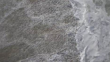 Aerial-drone-shot-of-sea-waves-crashing-in-the-beach